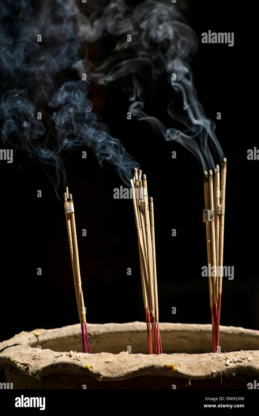 Bastoncini di incenso con fumo su sfondo nero Foto Stock