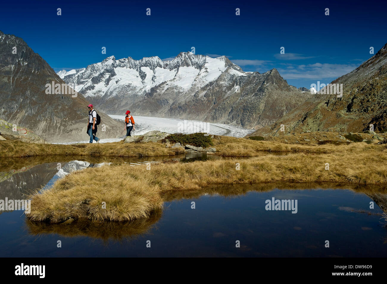 Lago di montagna e gli escursionisti in montagna Bettmerhorn, nella parte anteriore dei picchi del Bernese Oberland e il ghiacciaio di Aletsch, UNESCO Foto Stock
