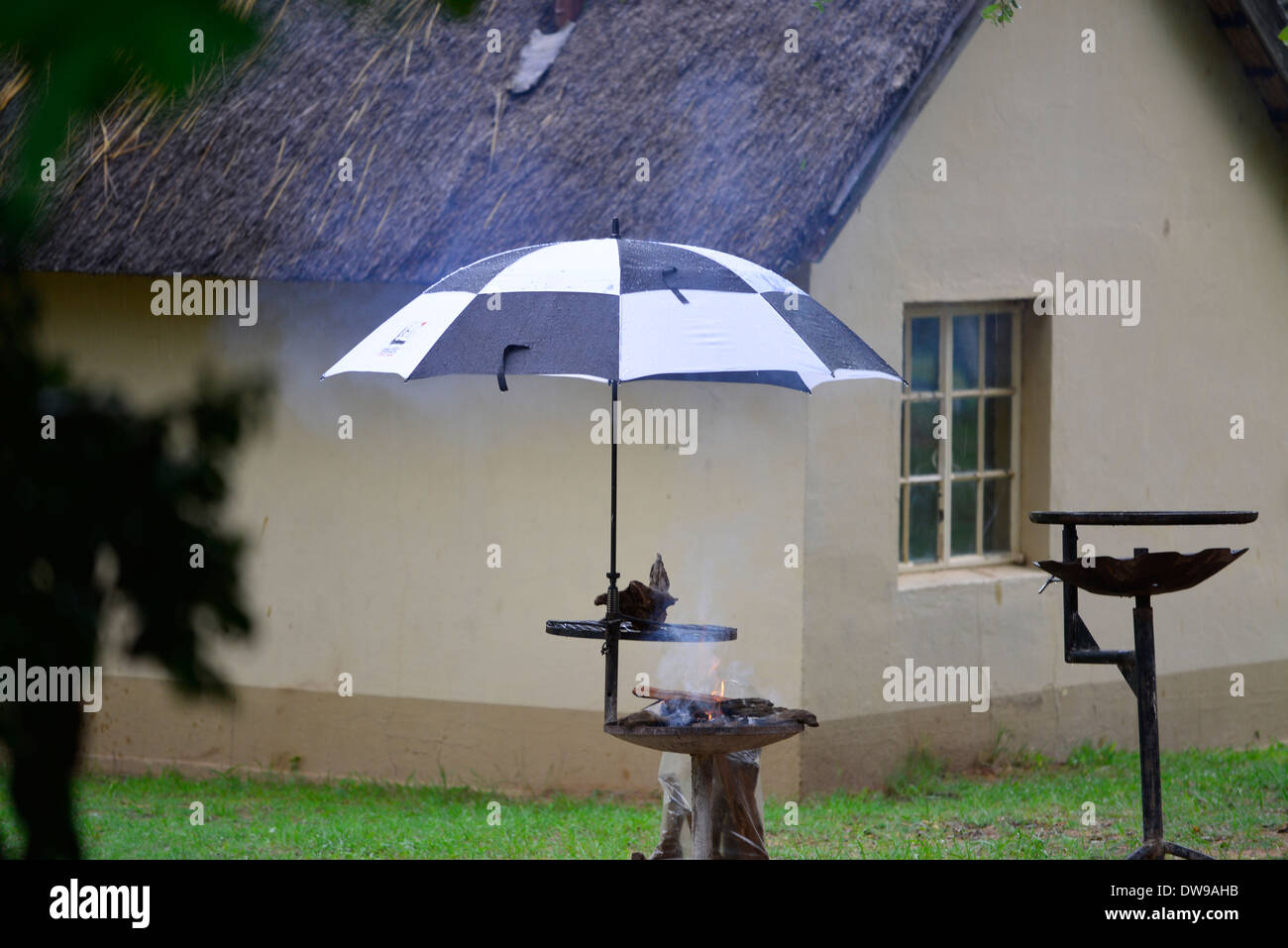 Braai barbecue o nel parco di Kruger, Sud Africa. Fire con ombrellone oltre a tenere fuori pioggia di carne. Foto Stock