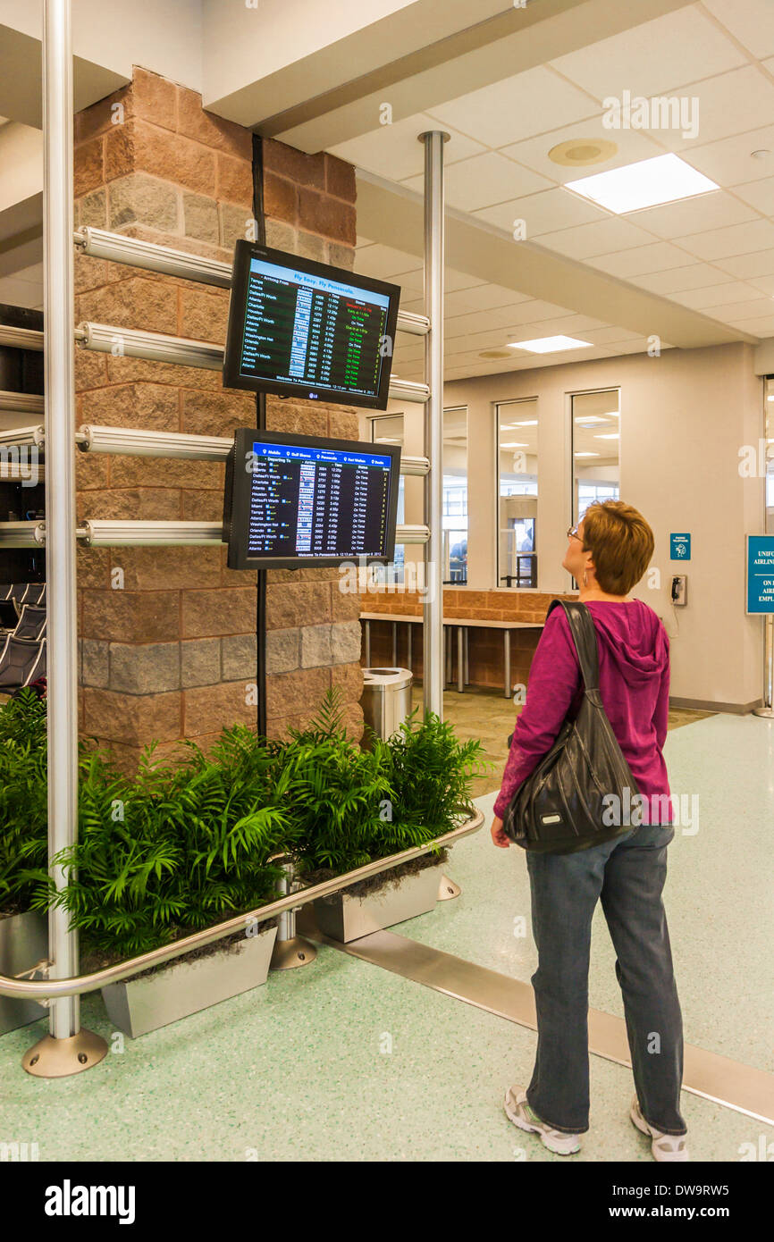 Donna che guarda un arrivo e partenza schermi di Pensacola International Airport in Pensacola, Florida Foto Stock