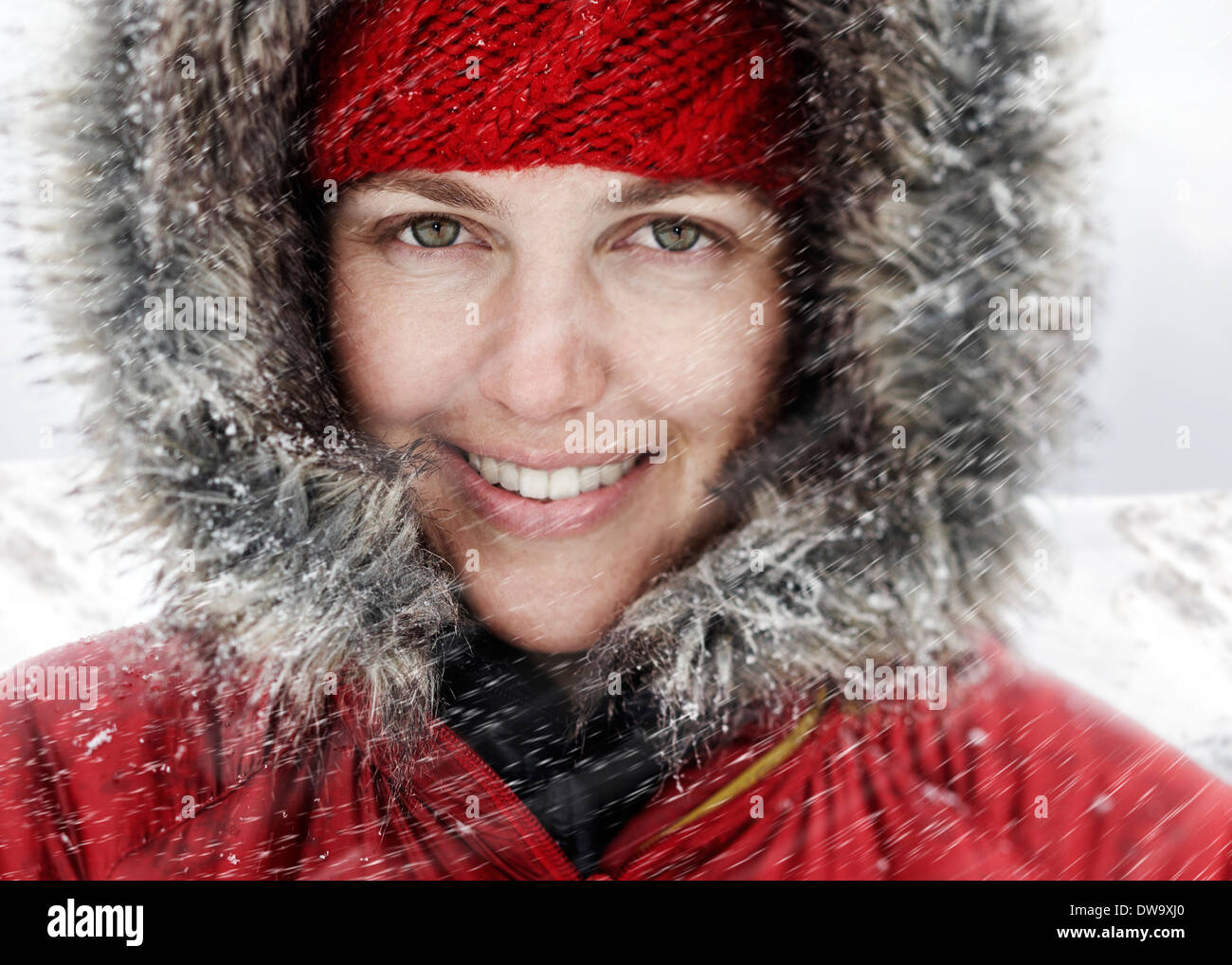 Close up ritratto di giovane donna in rosso del cofano nella neve Foto Stock