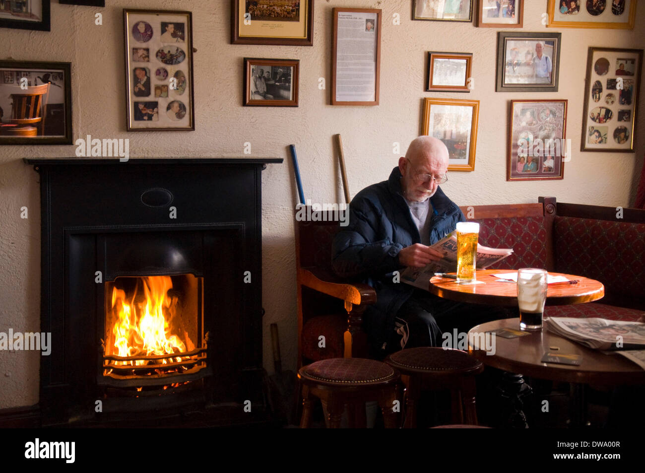 Un uomo gode di una pinta dall'incendio in Corner House Bar a Ardara, County Donegal, Irlanda Foto Stock