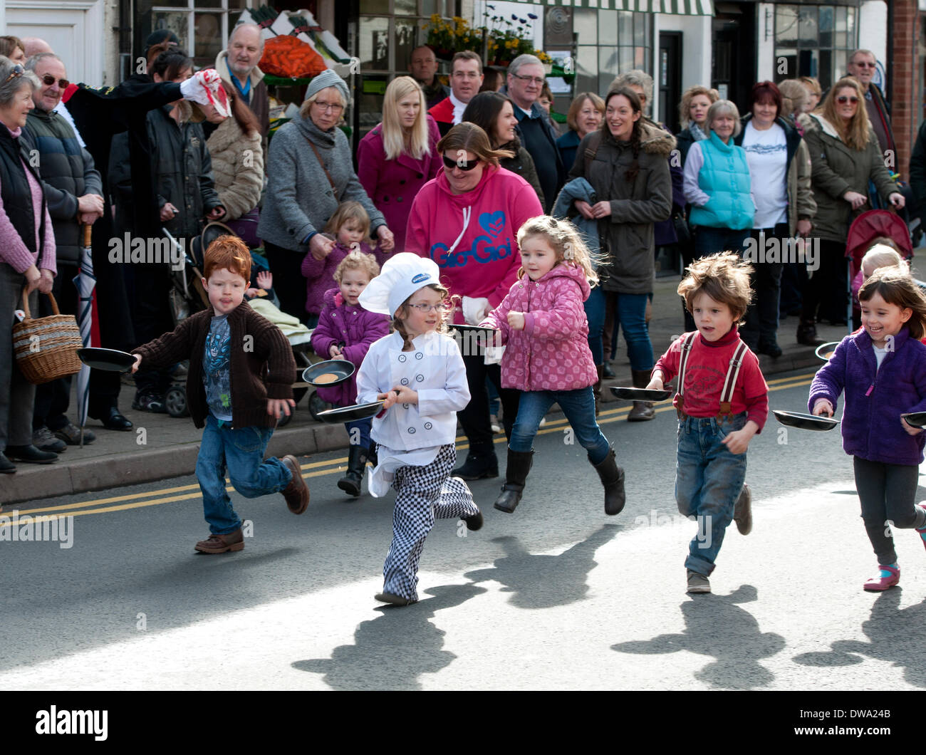 Alcester, Warwickshire, Inghilterra, Regno Unito. Il 4° marzo 2014. I bambini in gara uno dell annuale Martedì Grasso pancake gare svoltesi in Alcester High Street. Credito: Colin Underhill/Alamy Live News Foto Stock