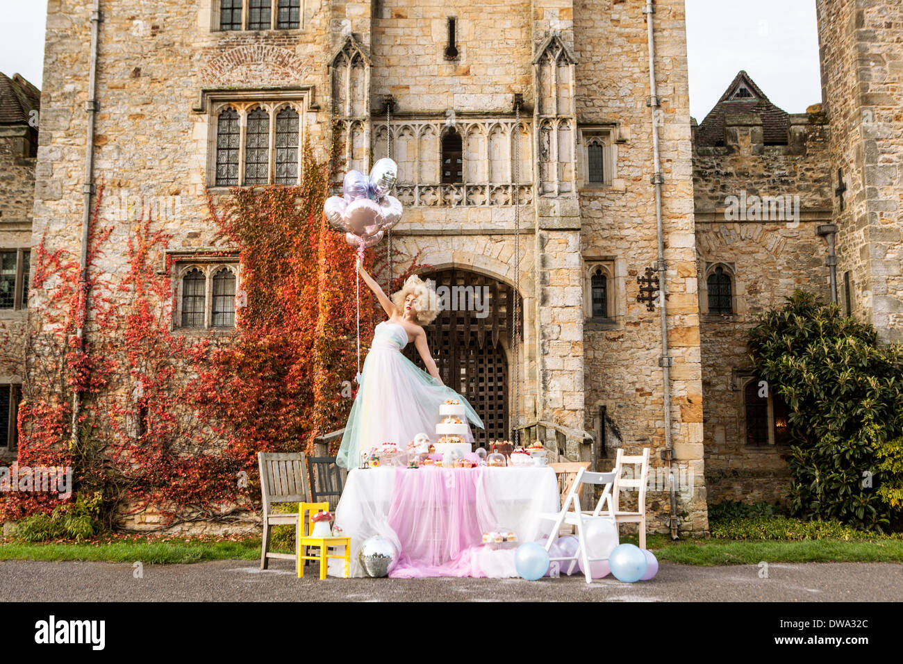Sposa in piedi sul tavolo al di fuori del castello, palloncini di contenimento Foto Stock