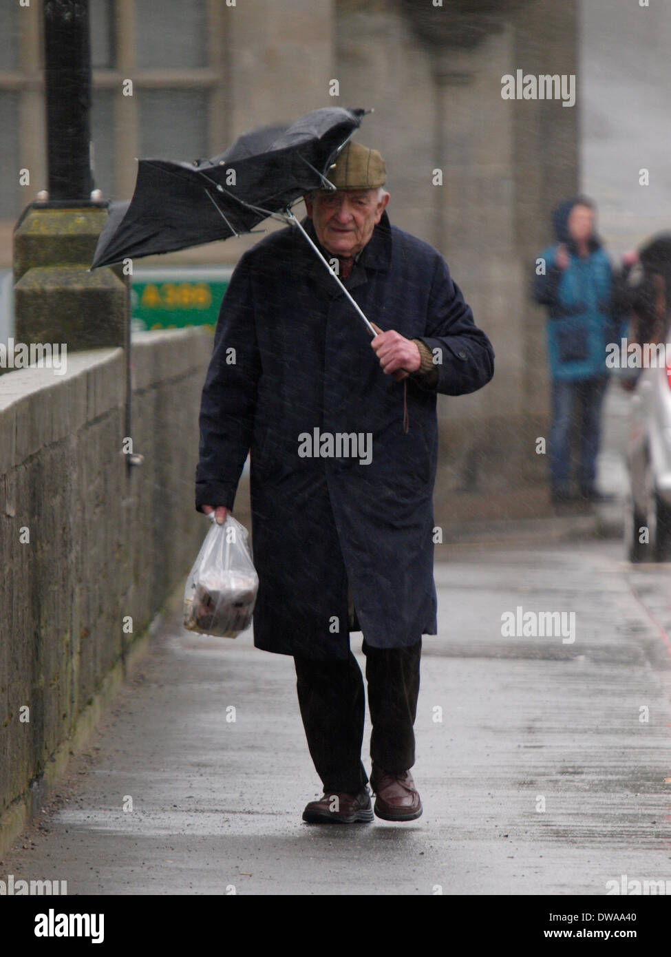 Il Vecchio Uomo con ombrello rotto sotto la pioggia e vento, Bideford, Devon, Regno Unito Foto Stock