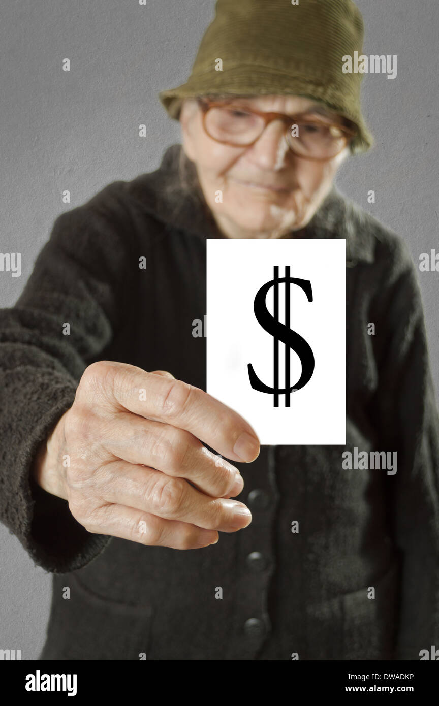 Donna anziana tenendo la scheda con impresso un segno di dollaro. Il fuoco selettivo sulla carta e le dita. Foto Stock