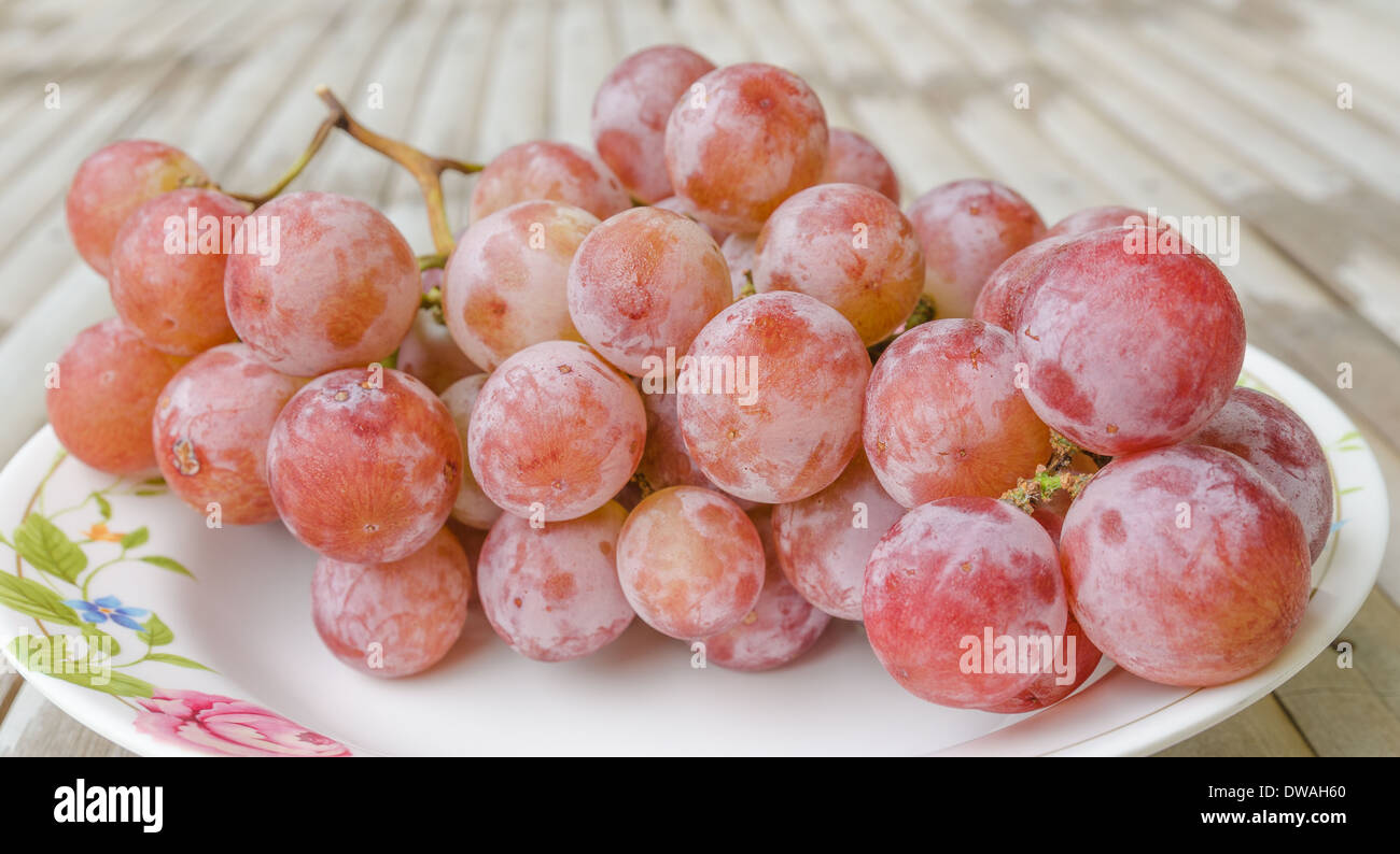 Uva rossa dolce mature sulla tabella di bambù Foto Stock