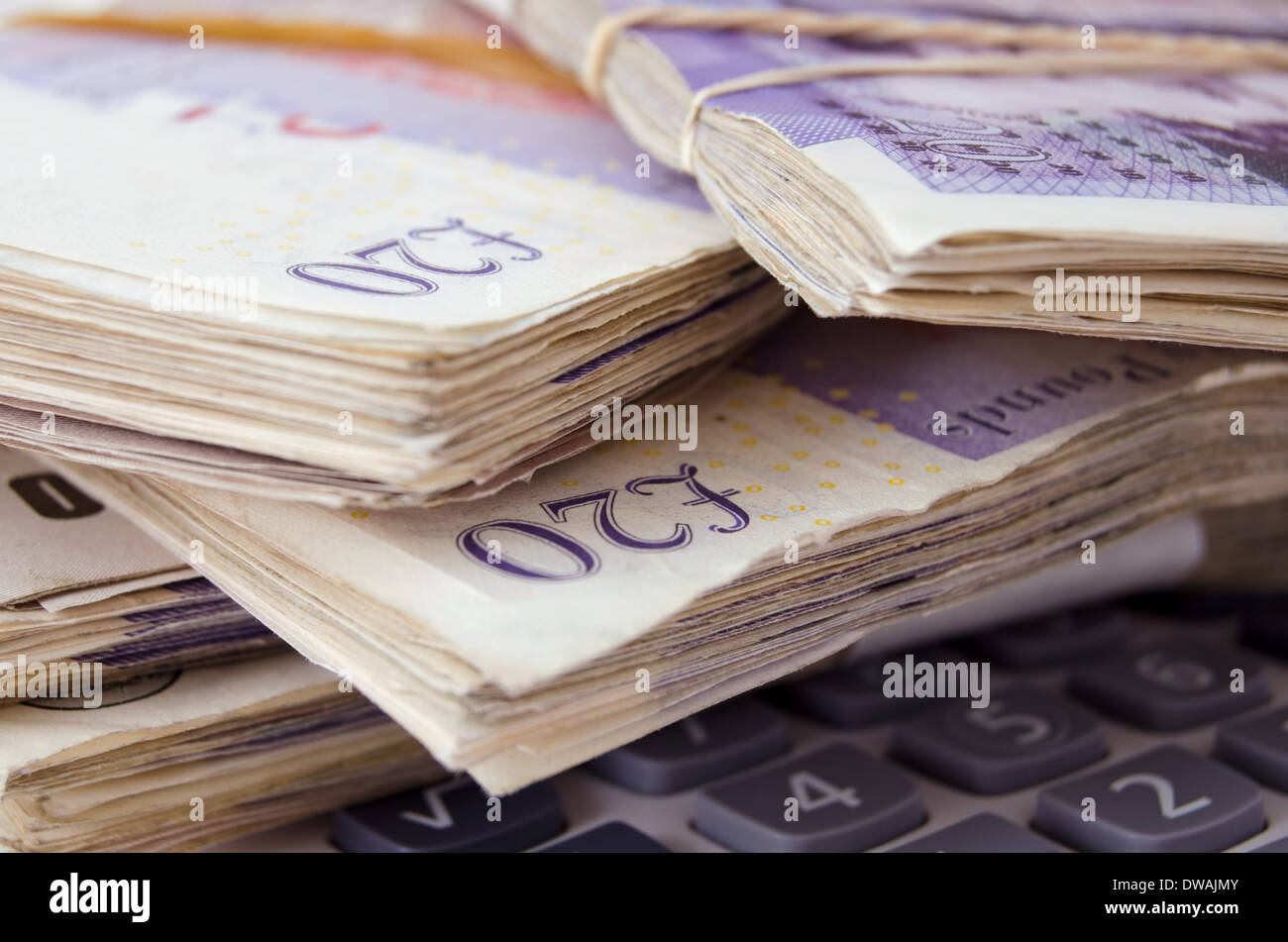 Fasci di venti pound note su una calcolatrice Foto Stock