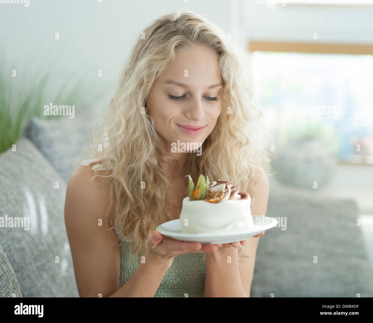 Giovane e bella donna che guarda la torta allettante in casa Foto Stock