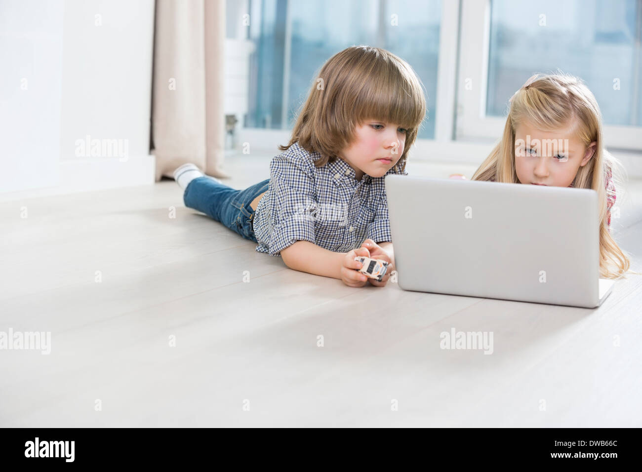 Fratello e Sorella utilizzando laptop sul pavimento a casa Foto Stock