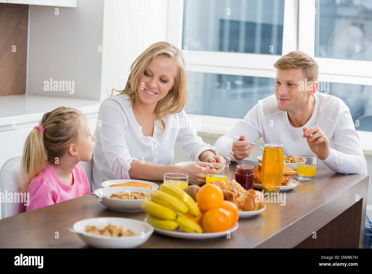 La famiglia felice di tre con la colazione a tavola Foto Stock
