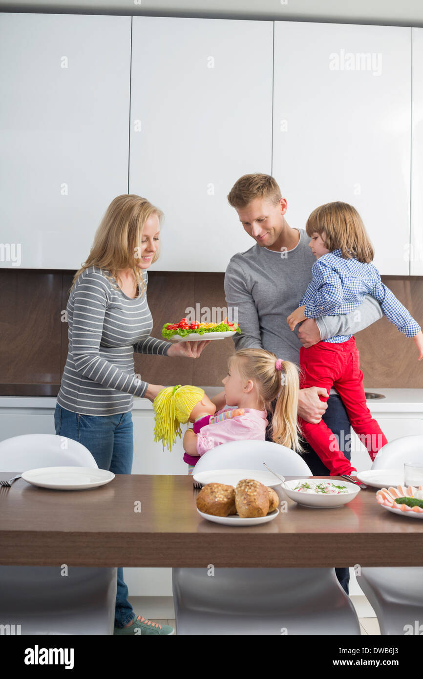 La famiglia felice con bambini aventi pasto nella cucina domestica Foto Stock