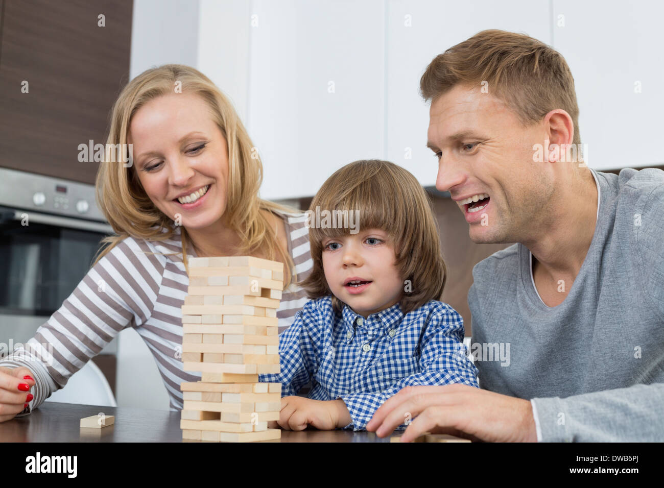 Genitori felici e figlio giocare con dei blocchi di legno a casa Foto Stock