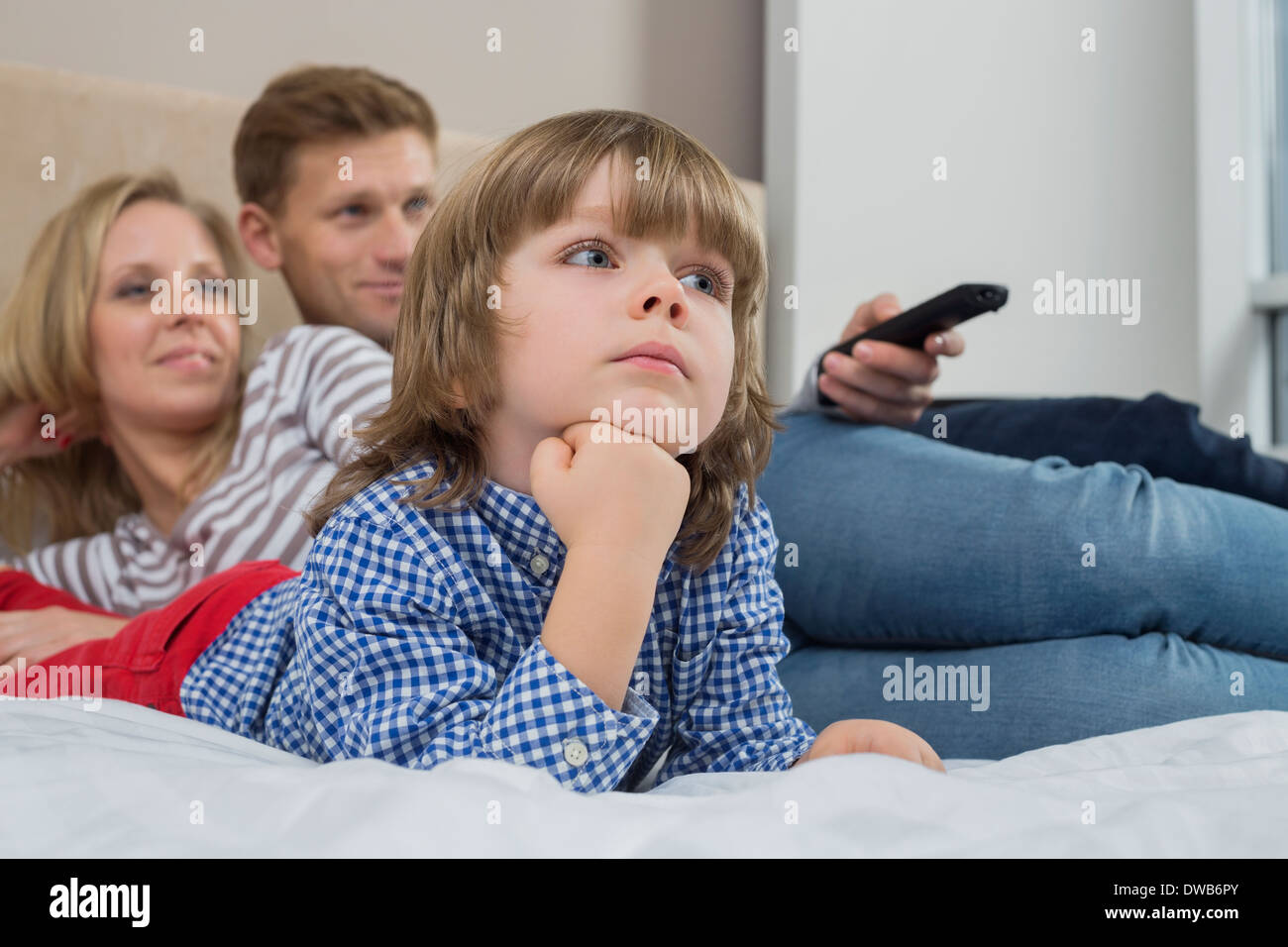 Famiglia a guardare la TV in camera da letto Foto Stock