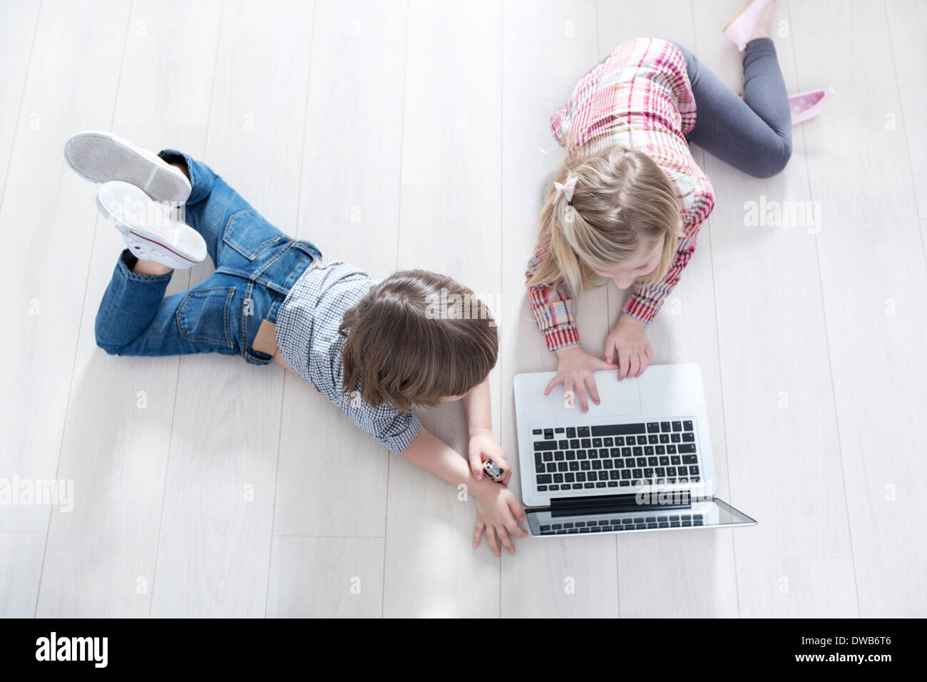 Angolo di Alta Vista del fratello e sorella utilizzando laptop sul pavimento a casa Foto Stock