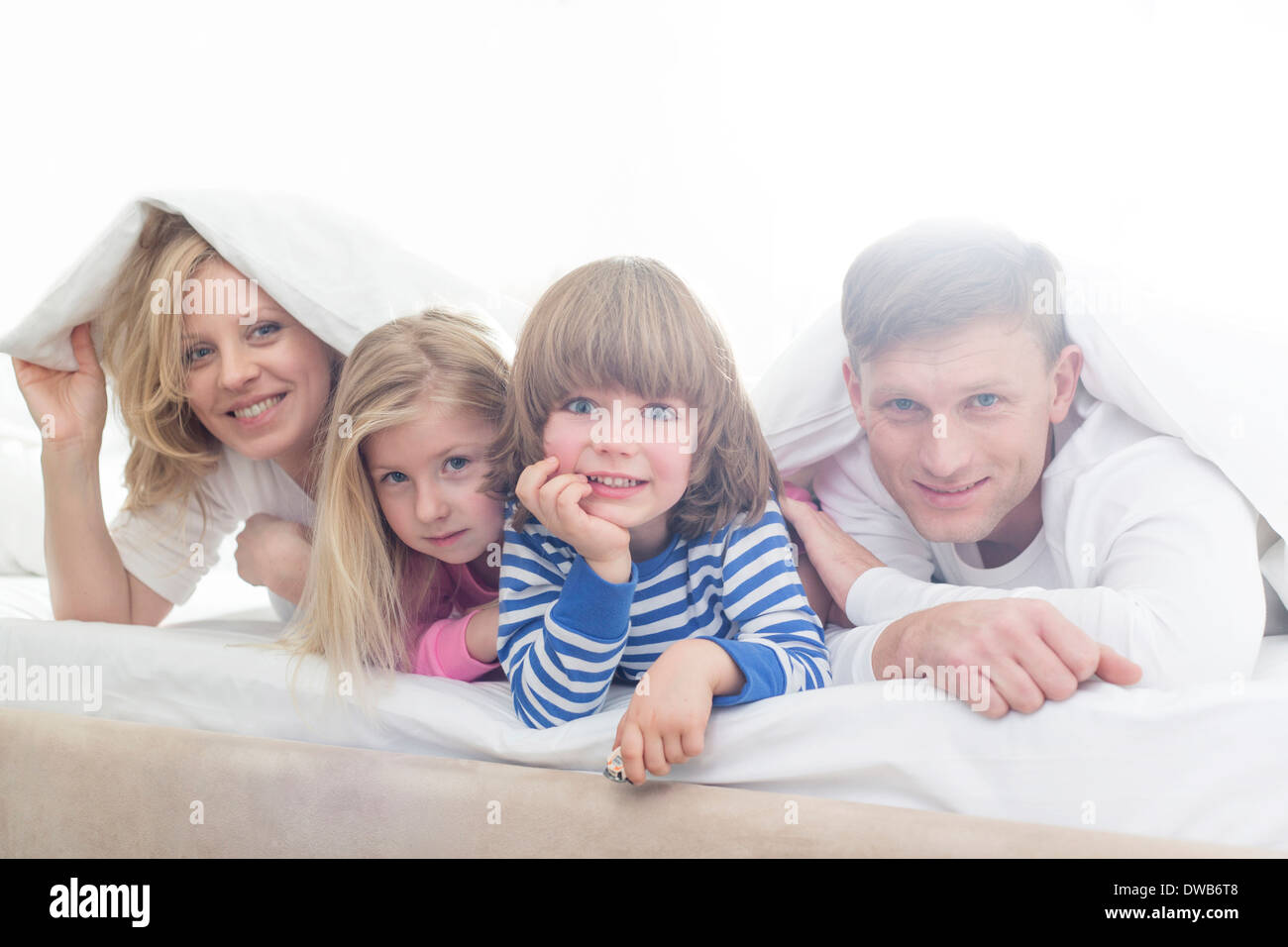 Ritratto di genitori felici e bambini giacente sotto la copertura per il letto Foto Stock