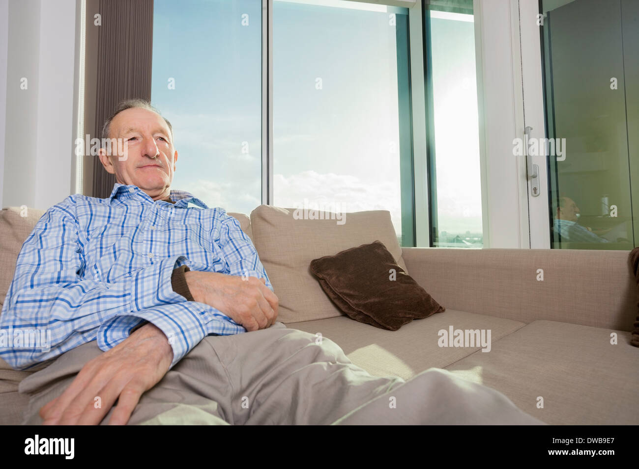 Senior uomo rilassante sul divano di casa Foto Stock