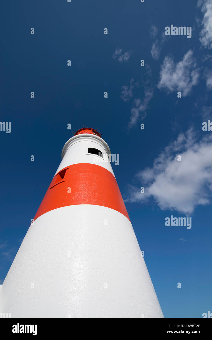 Dettaglio shot della torre di un rosso e bianco faro stretching fino a un profondo cielo blu. Foto Stock