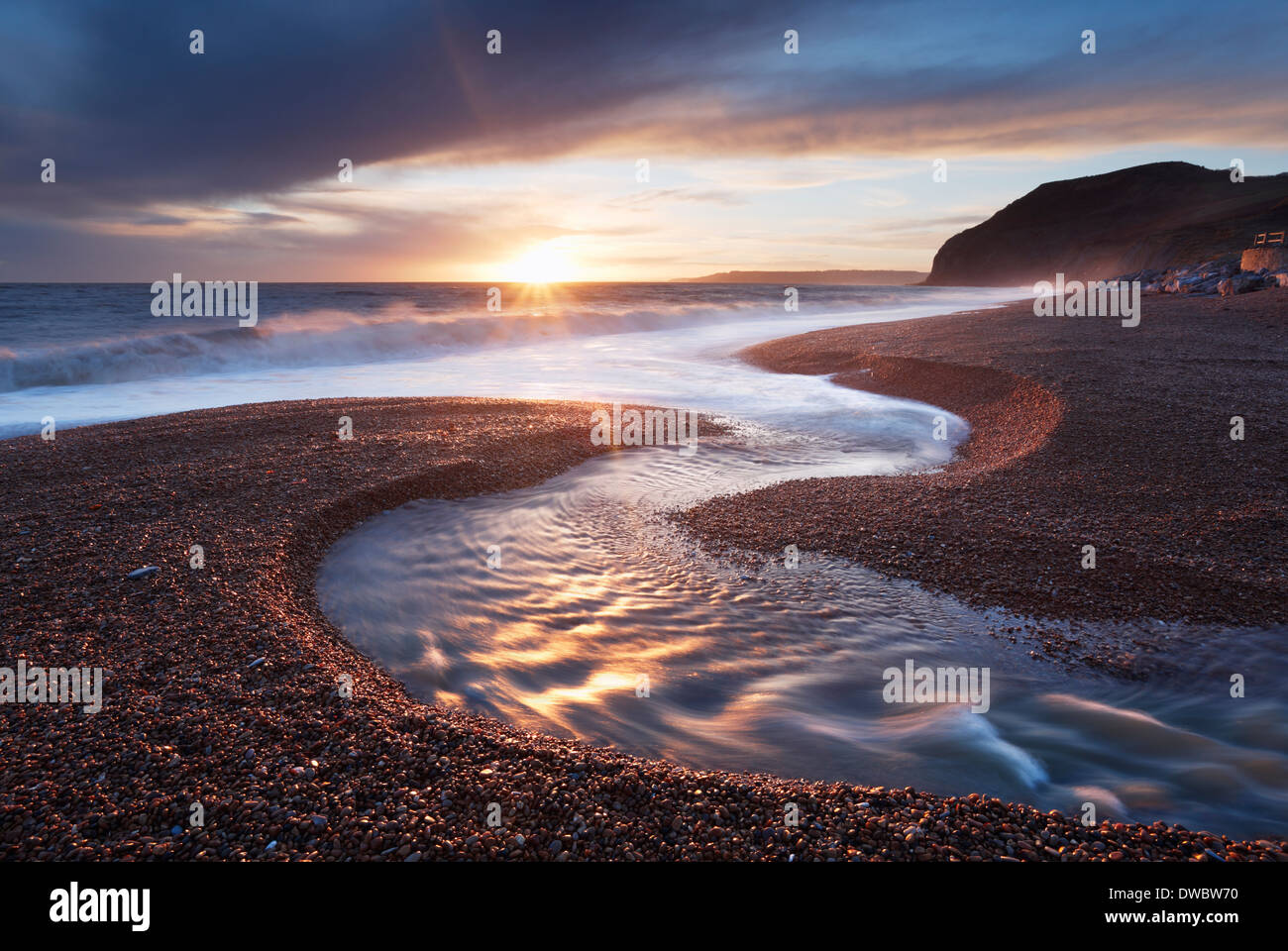 Winniford sul fiume che scorre verso il mare a Seatown spiaggia con scogliere di Golden Cap in distanza. Jurassic Coast. Il Dorset. Regno Unito. Foto Stock