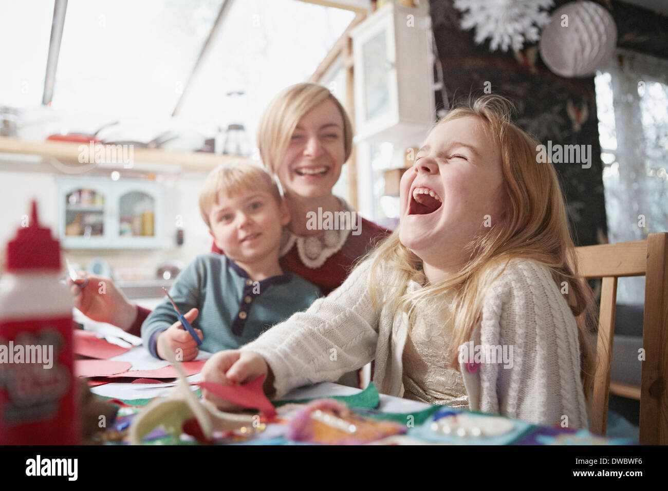 Madre e due bambini di produzione artigianale al tavolo della cucina Foto Stock