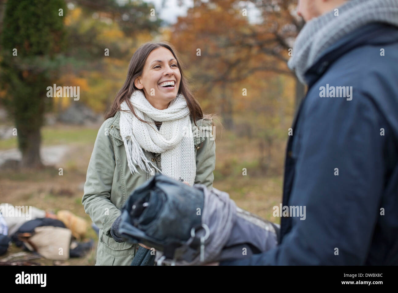 Donna felice in giacca invernale e sciarpa guardando l uomo durante il campeggio Foto Stock