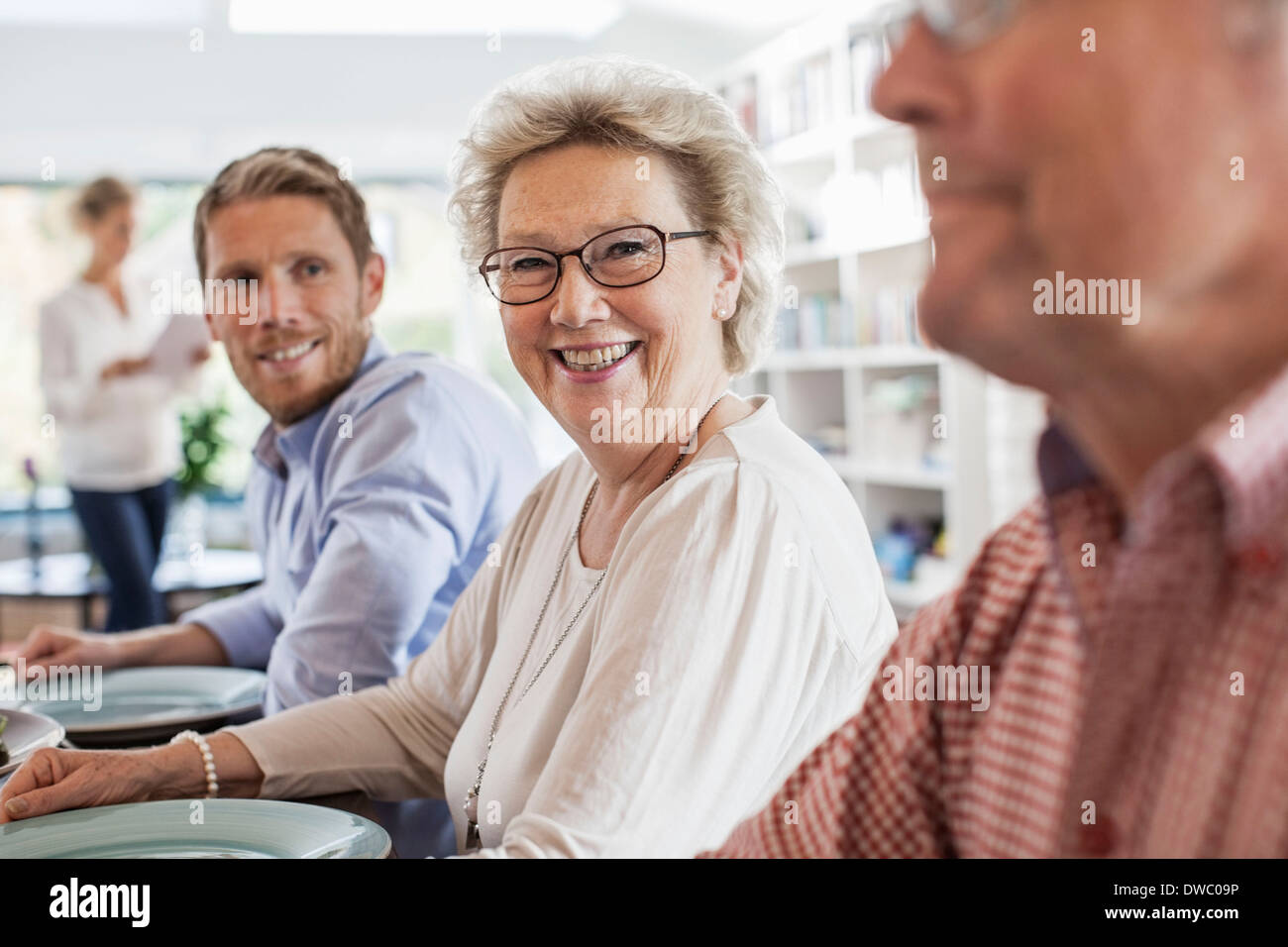 Ritratto di felice senior donna seduta con la famiglia al tavolo da pranzo Foto Stock