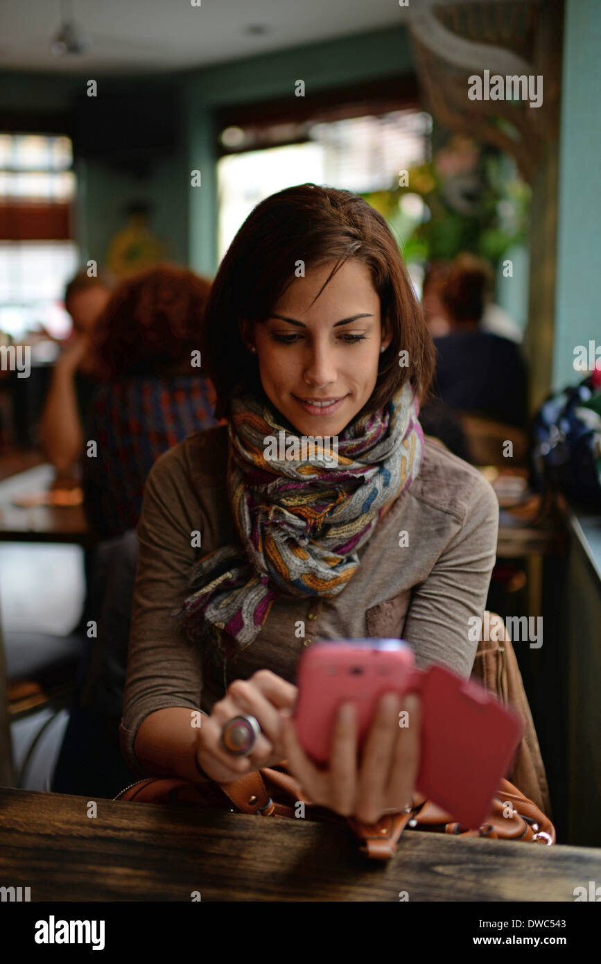 Attraente giovane donna utilizzando il telefono cellulare in cafe Foto Stock