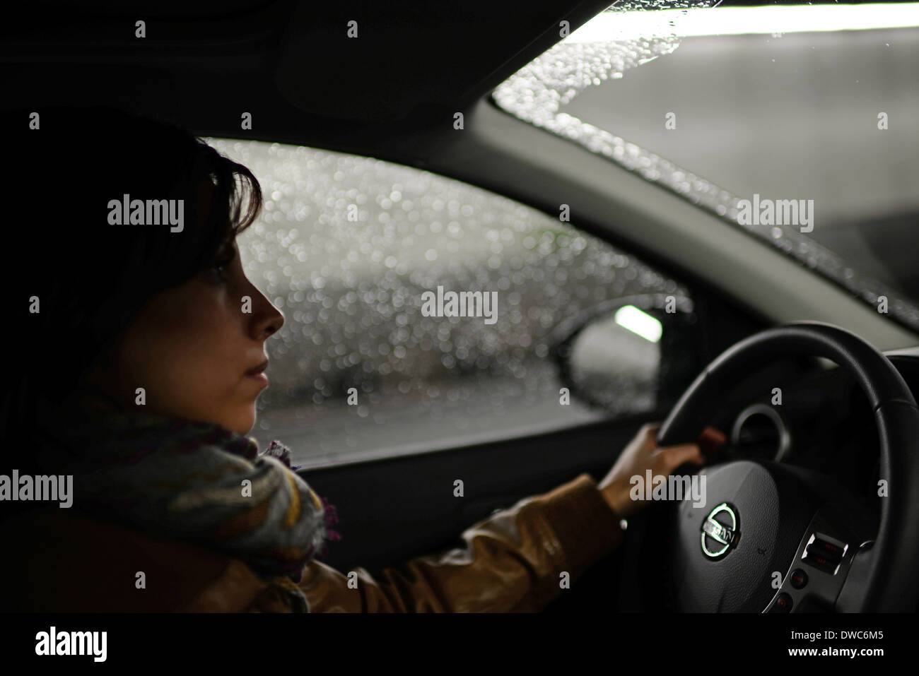 Giovane donna alla guida di auto in giorno di pioggia Foto Stock