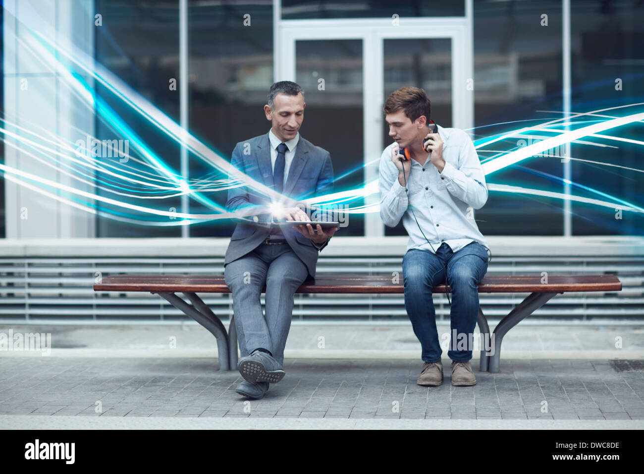 Imprenditore e giovane uomo guarda la tavoletta digitale e le onde di illuminazione Foto Stock