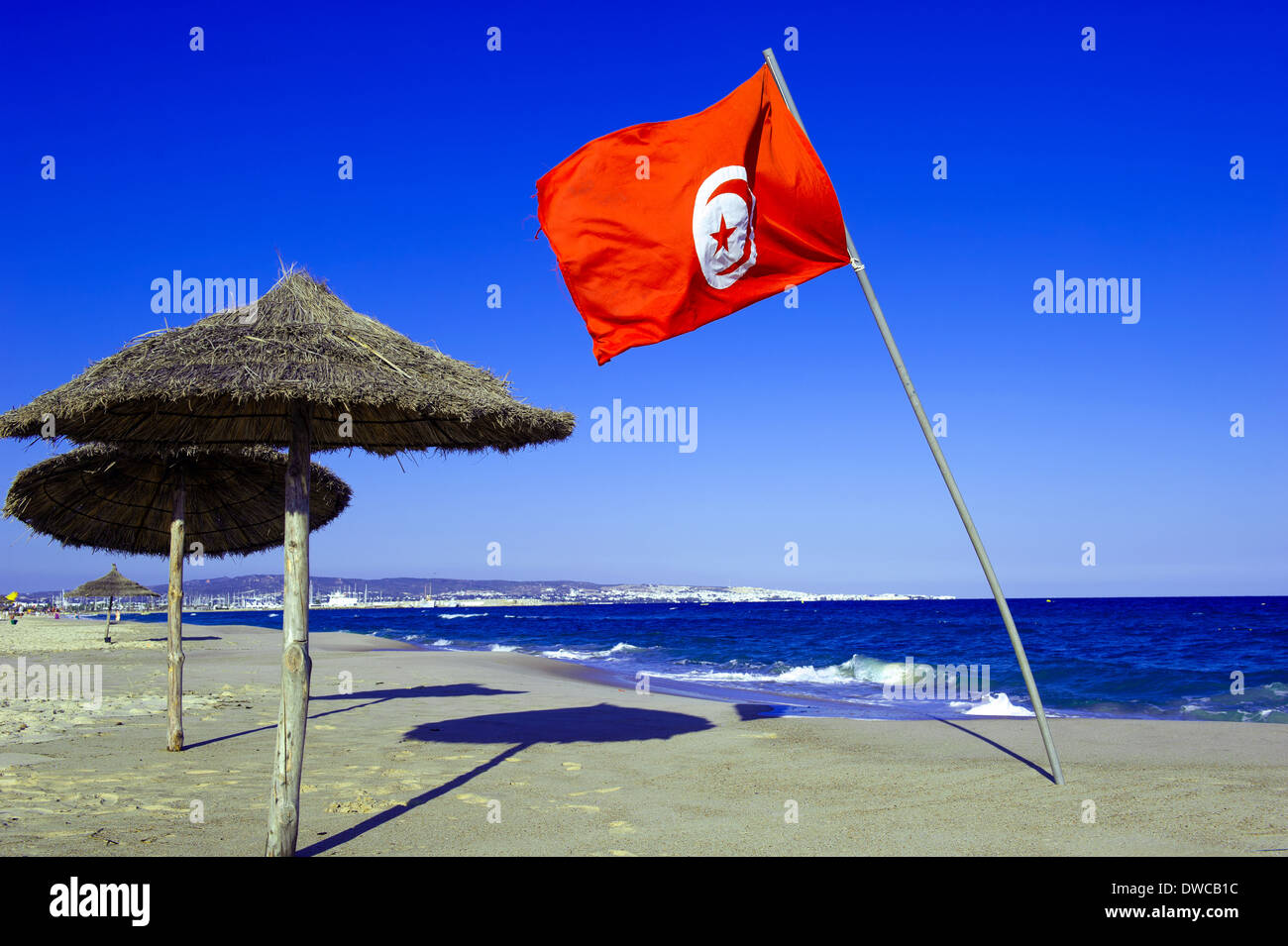 Il Nord Africa, Tunisia, Capo Bon, Hammamet. Bandiera tunisina fluttuante nel vento sulla spiaggia di Hammamet. Foto Stock