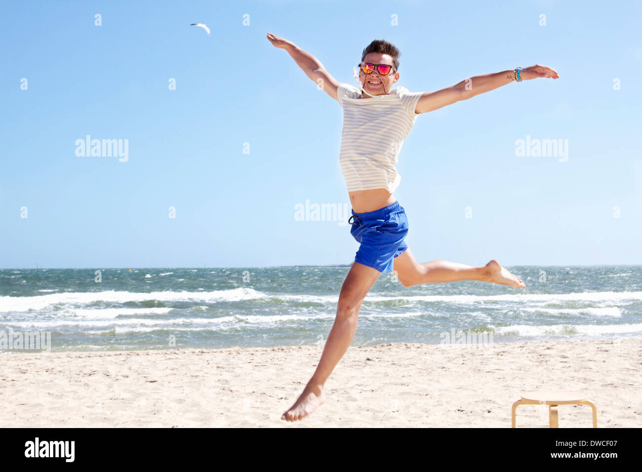 Giovane uomo che saltava metà aria sulla spiaggia, il Port Melbourne, Melbourne, Australia Foto Stock