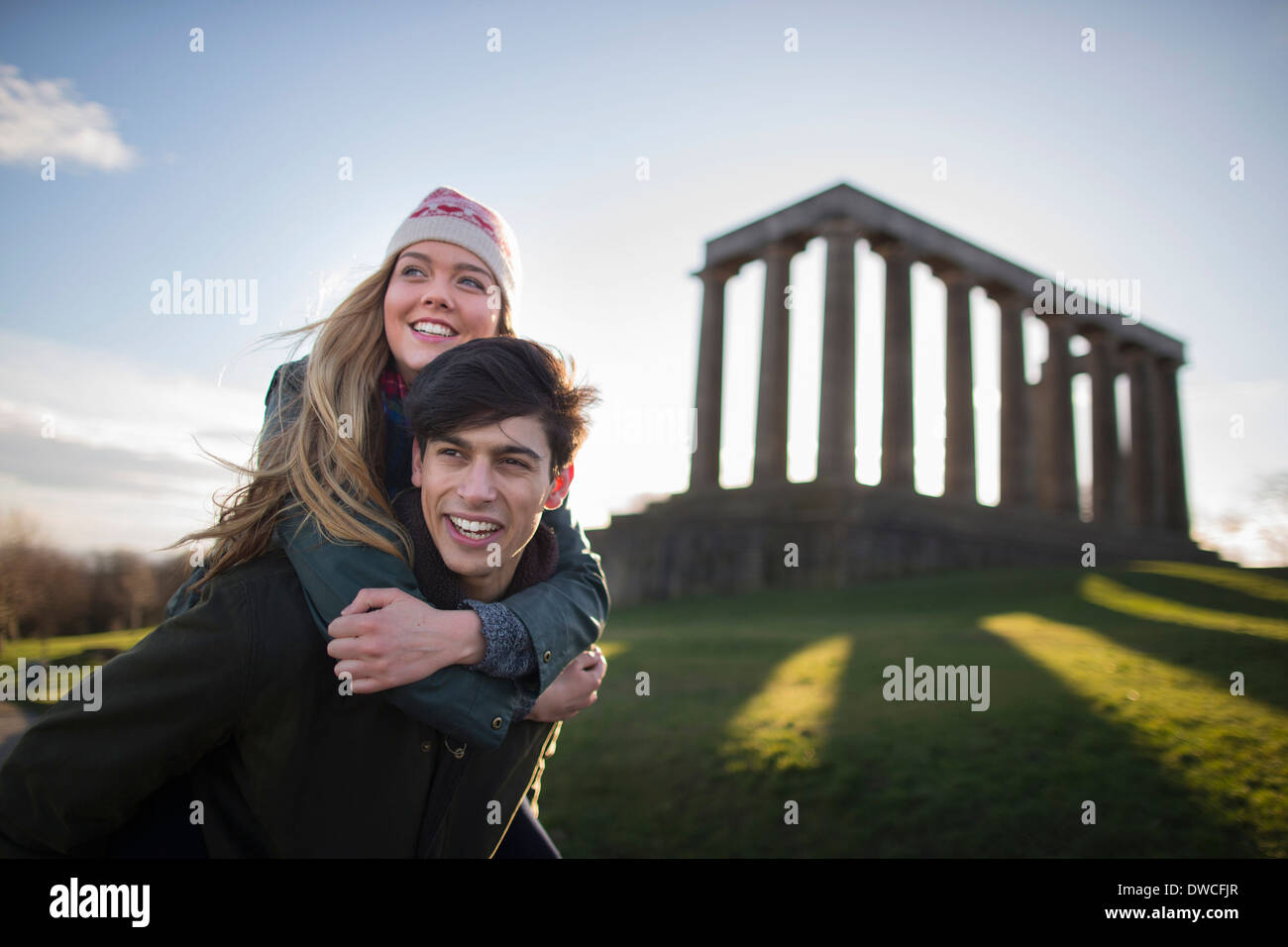 Una giovane coppia su Calton Hill con lo sfondo del Monumento Nazionale di Scozia in Edinburgh Foto Stock