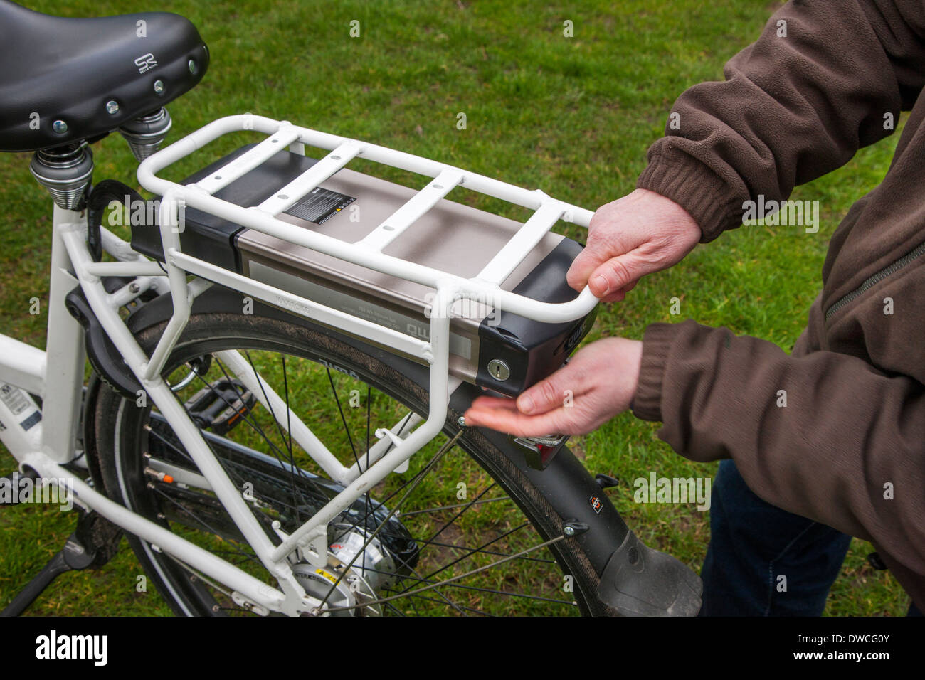 L'uomo mettendo la batteria agli ioni di litio a sotto il supporto posteriore del rack pedelec / e-bike / Bicicletta elettrica Foto Stock