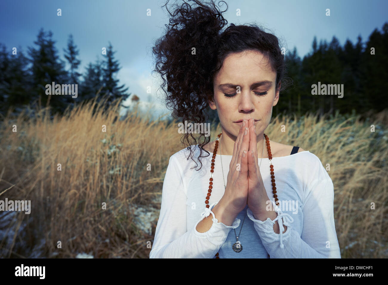 Metà donna adulta meditando nella foresta Foto Stock