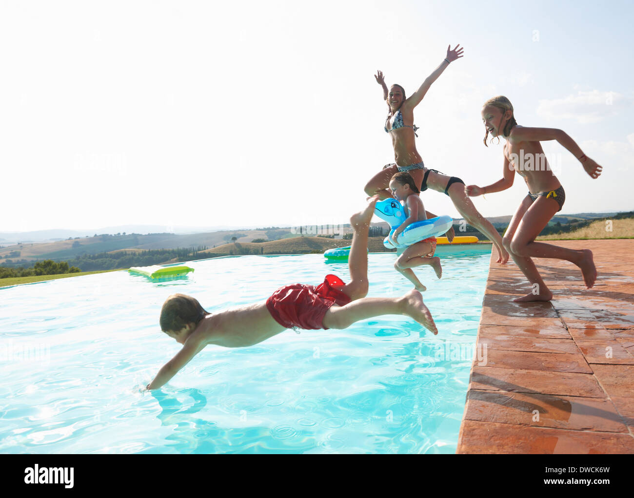 Cinque persone il salto in piscina Foto Stock