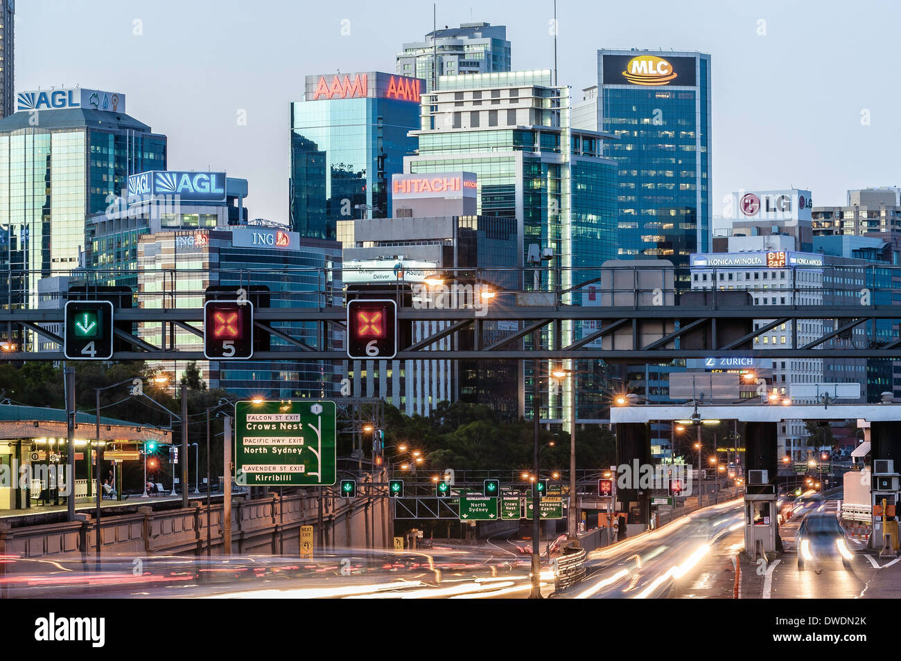 Cars andare attraverso i cancelli di pedaggio sul ponte del Porto di Sydney in Australia con edifici di uffici sulla sponda nord dietro Foto Stock