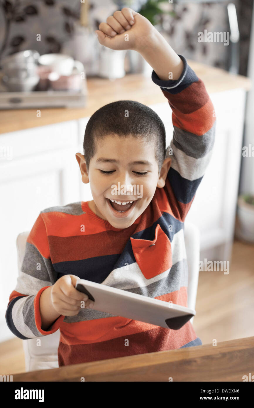 Ragazzo di successo utilizzando tavoletta digitale in casa Foto Stock