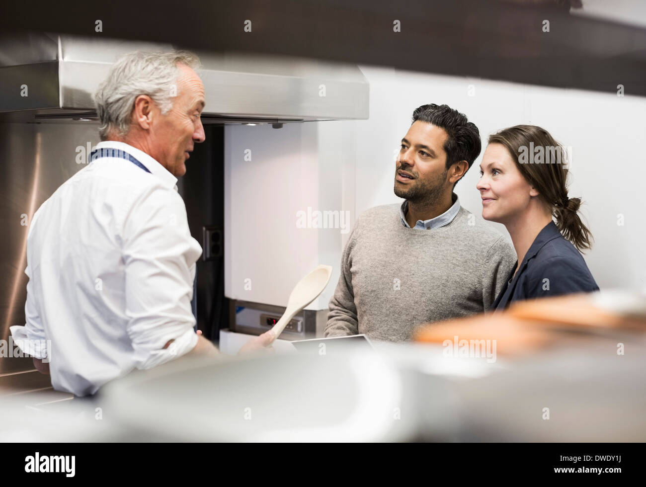 Lo chef a parlare con la gente di affari in cucina commerciale Foto Stock