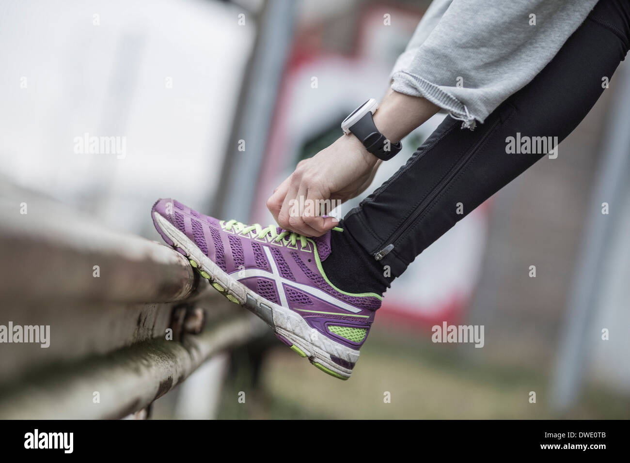 Sezione bassa di donna laccio di legatura della calzatura sportiva su parapetto Foto Stock