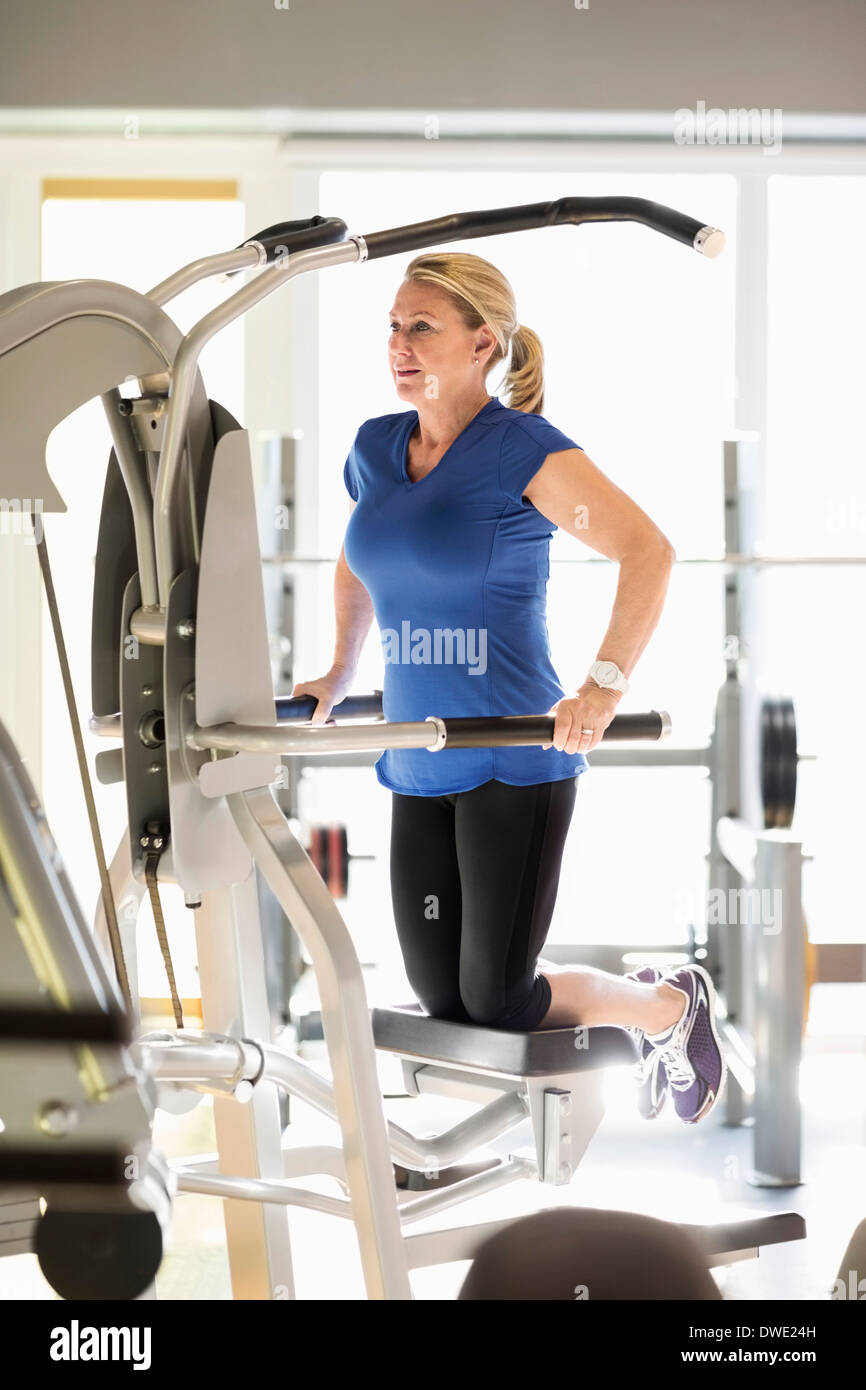 Senior donna esercita sul pull-up assistere la macchina a palestra Foto Stock