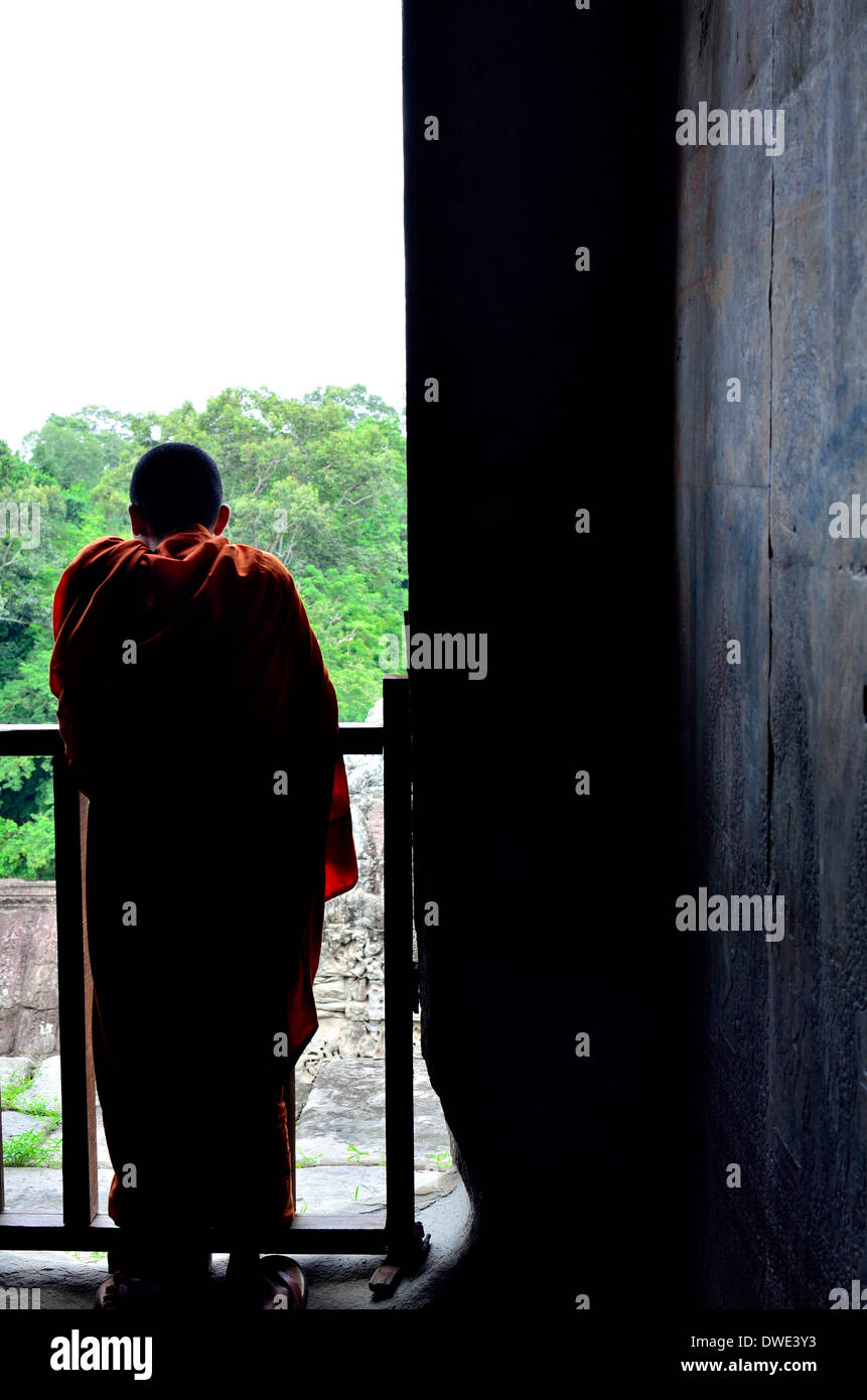 Un monaco buddista in visita dalla Thailandia in pellegrinaggio guarda fuori del tempio di Angkor finestra attraverso la giungla della Cambogia Foto Stock