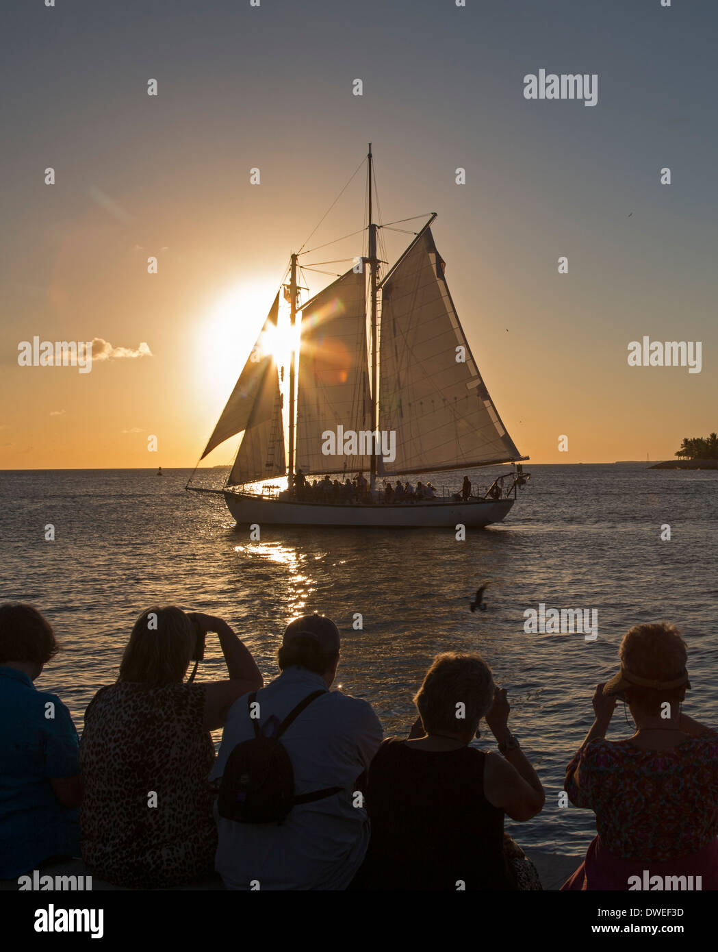 Key West, Florida - turisti si riuniscono in Mallory Square e ride barche a vela per ammirare il tramonto. Foto Stock