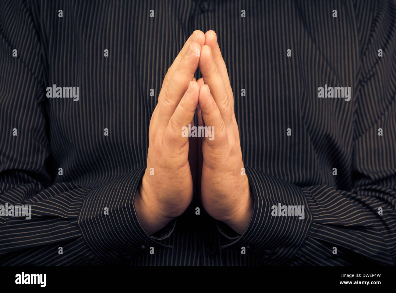 Primo piano della preghiera uomo bianco in maglietta scura Foto Stock