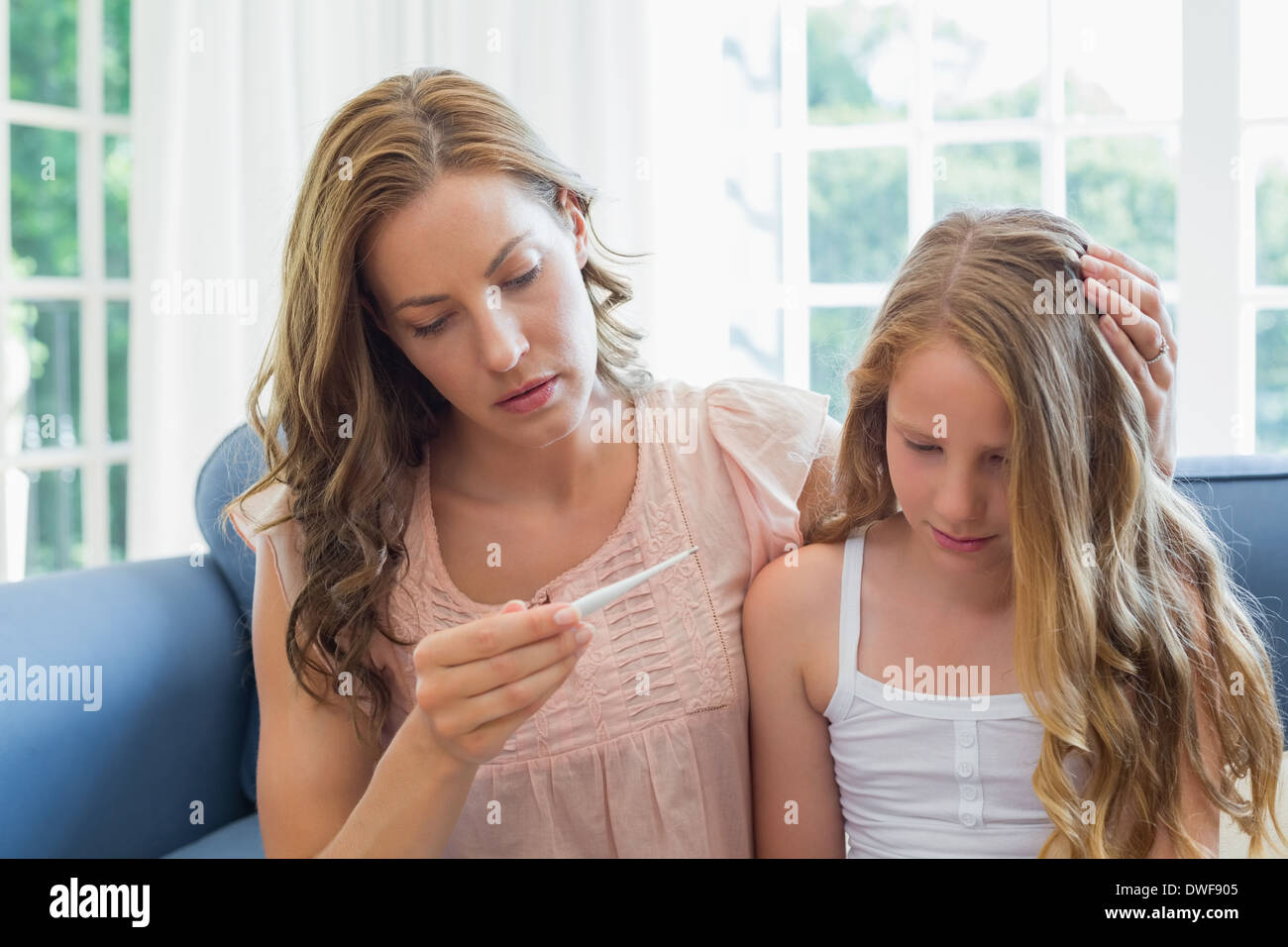 Madre guardando il termometro con bambino malato Foto Stock