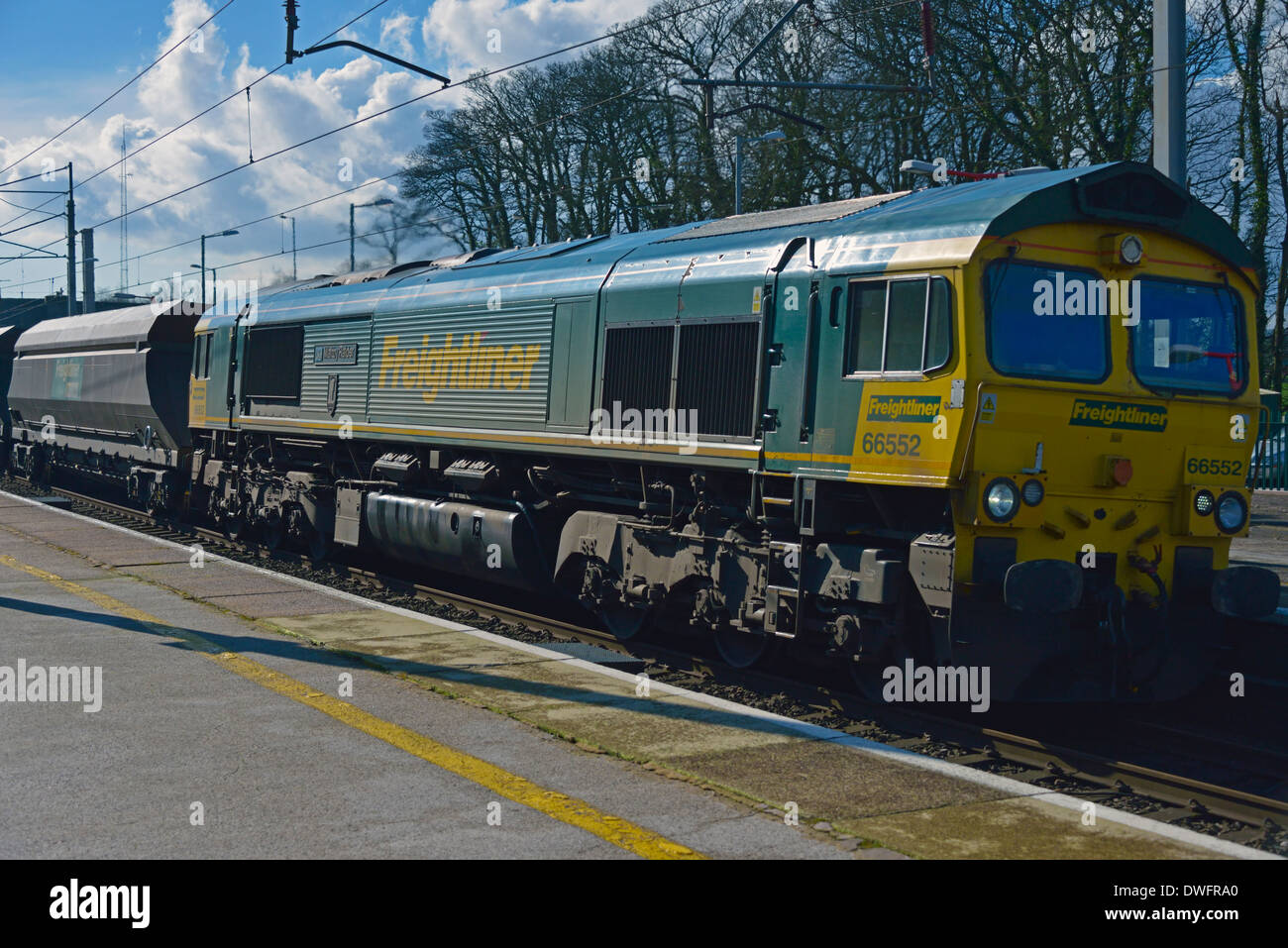 Freightliner Classe 66 locomotore con carichi pesanti camion a velocità. Stazione Oxenholme, Linea principale della costa occidentale, Cumbria, England, Regno Unito Foto Stock