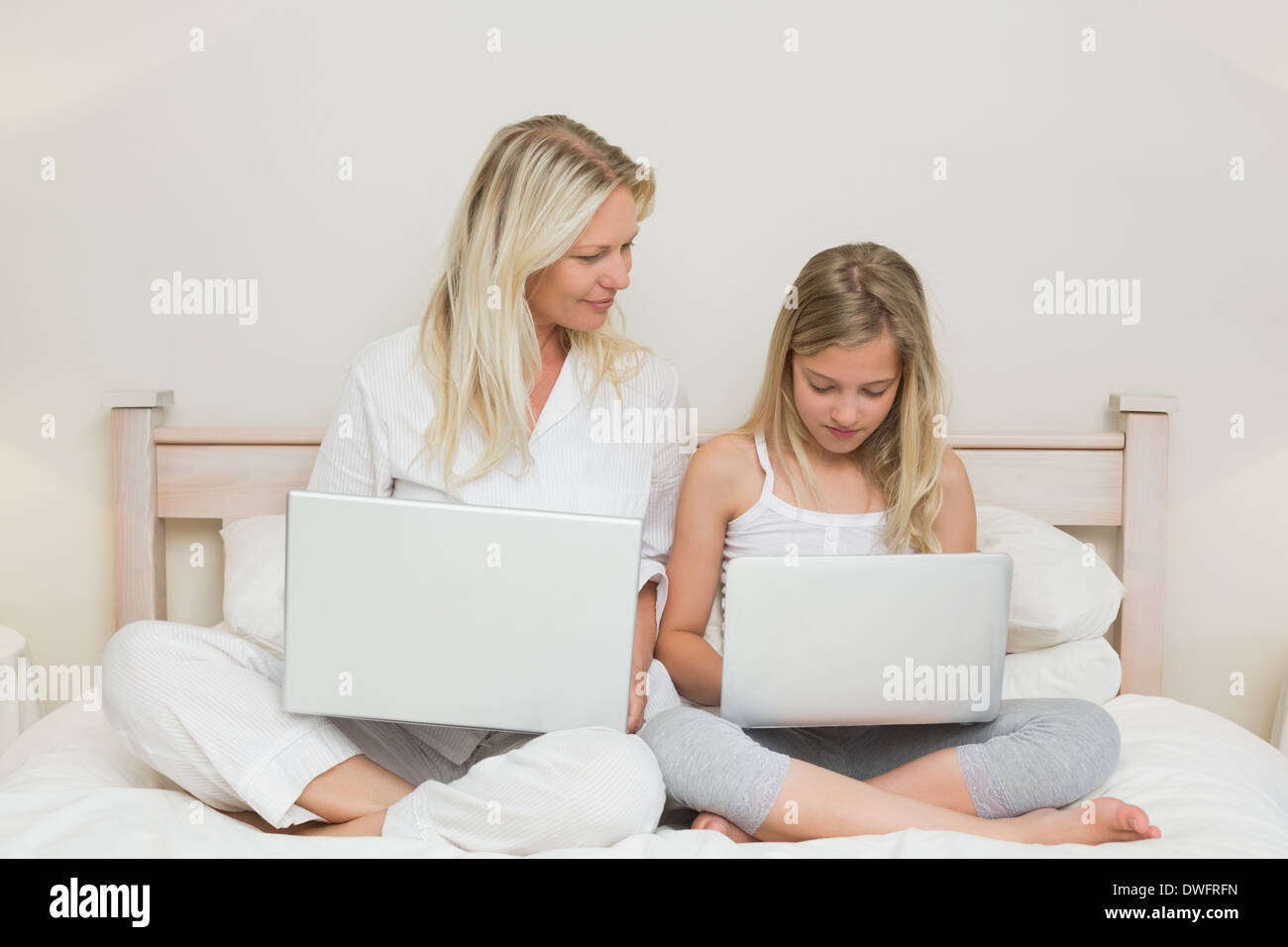 Madre e figlia utilizzando computer portatili a letto Foto Stock