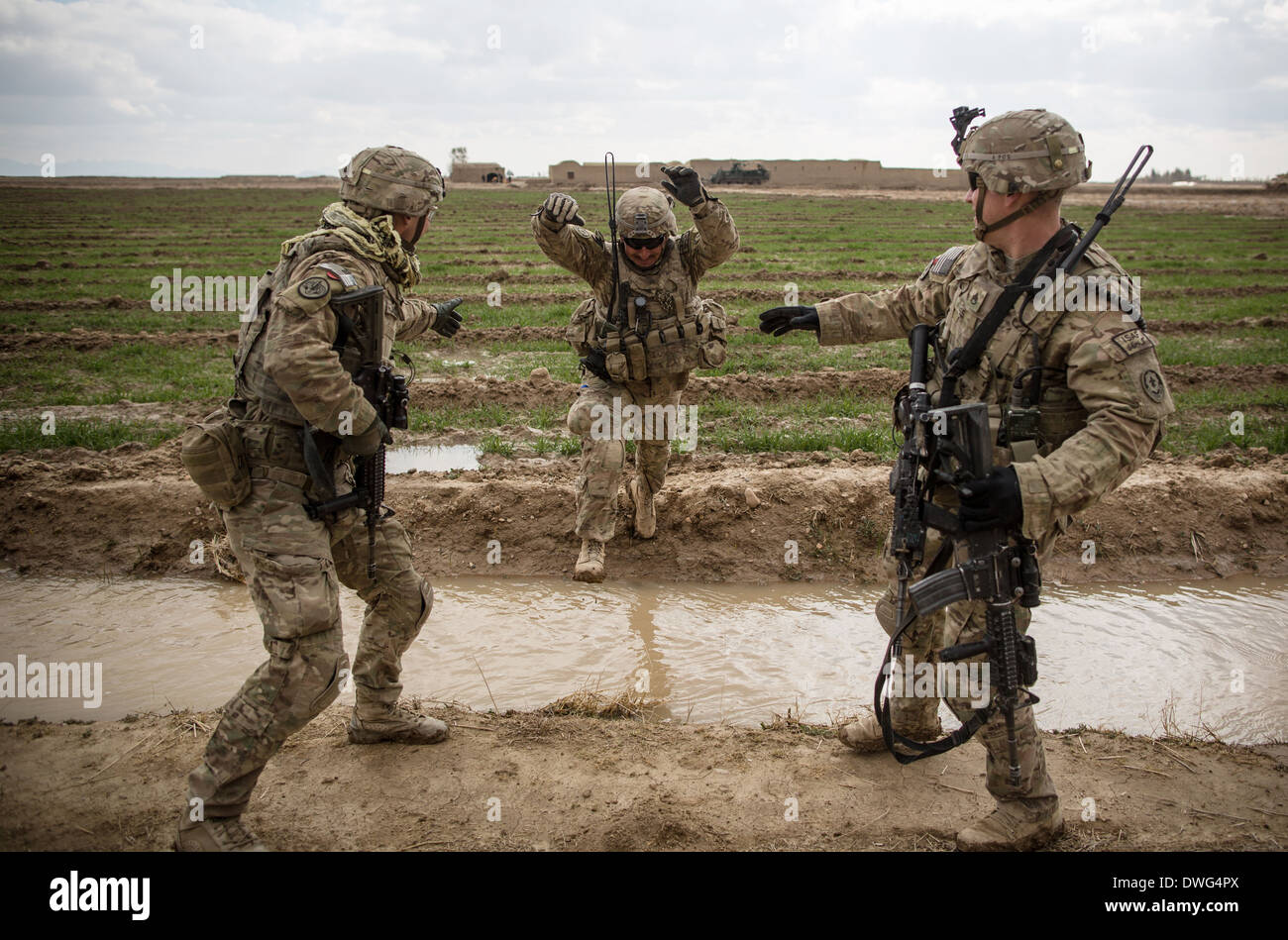 Noi soldati dell esercito saltare attraverso un fosso di irrigazione durante una pattuglia di ricognizione come parte di Operazione Alamo Scout Febbraio 12, 2014 nella provincia di Kandahar, Afghanistan. Foto Stock