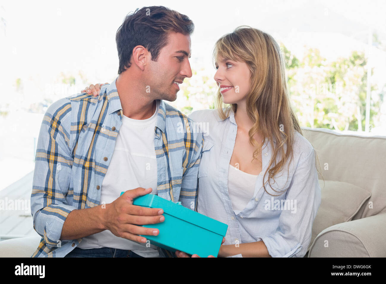 Amare giovane con confezione regalo seduto sul divano Foto Stock