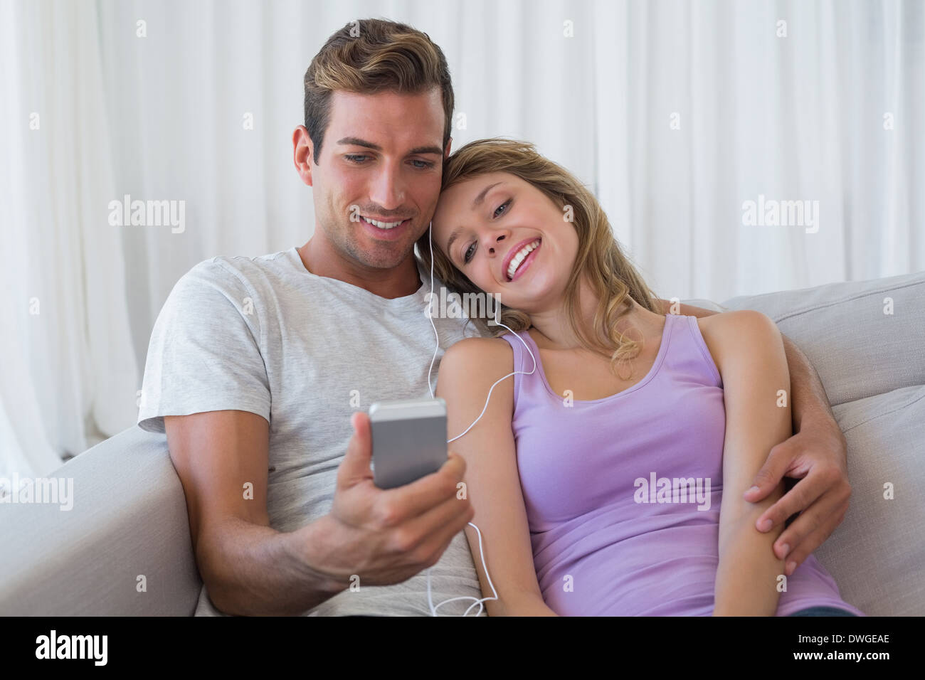 Giovane ascoltando musica con il telefono cellulare sul lettino Foto Stock