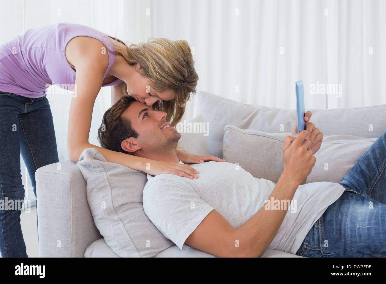 Moman kissing mans fronte mentre lui con tavoletta digitale Foto Stock